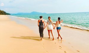 group of friends walking on the beach sand